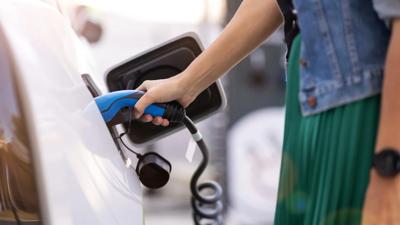 Electric car charging at a station, ACF logo, net zero emissions text.