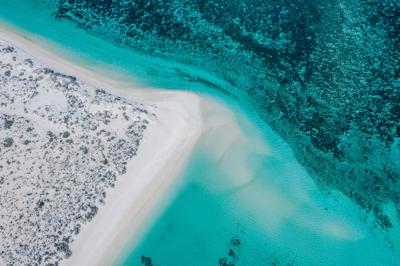 Aerial view of Ningaloo Reef, turquoise water, coral formations, and coastline.