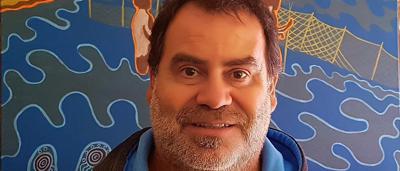 Woman in a white coat, holding a clipboard, smiling, in a lab setting.