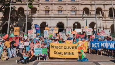 Protest banner, crowd, Palmer, Australian flag, sky.