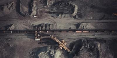 Coal mine landscape with machinery, smoke, and open pit.