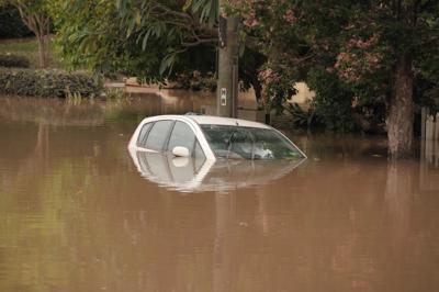 Floodwaters inundate Brisbane, Australia. Houses submerged, cityscape visible.