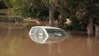 Floodwaters inundate Brisbane, Australia. Houses submerged, cityscape visible.
