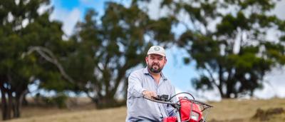 Two men smiling, posing outdoors. One holds a camera.