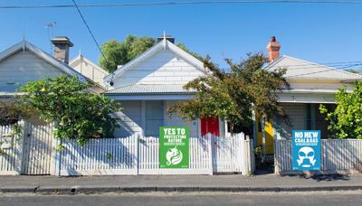 Two signs on a wooden fence, one with text, the other blank.