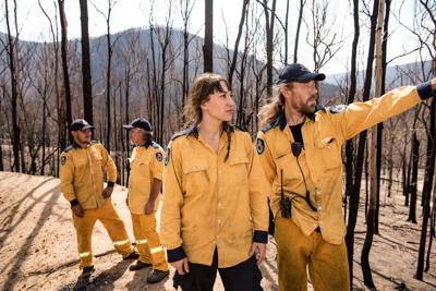 Woman firefighter in NSW, wearing protective gear, smiling.