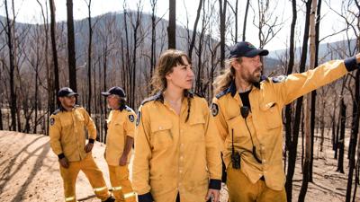 Woman firefighter in NSW, wearing protective gear, smiling.