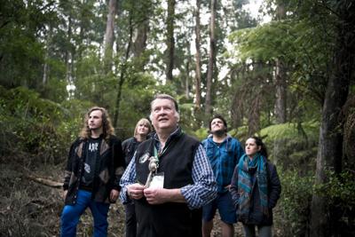 Woman in a field, smiling, with a backdrop of trees and a blue sky.