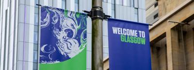 Glasgow cityscape with a bridge over a river, featuring buildings and a cloudy sky.