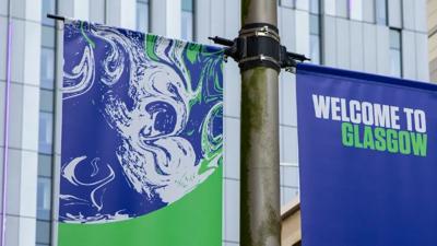 Glasgow cityscape with a bridge over a river, featuring buildings and a cloudy sky.