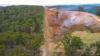 Aerial drone view: Deforestation, half bushland, half cleared land, burning piles, bulldozer.