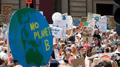 A crowd of people at a rally, holding signs and banners, with a focus on the group.
