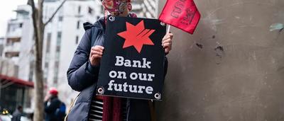 Protest banner, crowd, Australian flag, NAB building in background.
