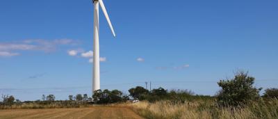 Woman in white coat, holding a tablet, smiling, looking at a screen, in a lab setting.