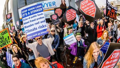 Header image: People protesting, holding signs, against a backdrop of a coal mine.