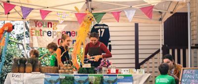 People at market stall, fundraising for ACF, banner visible.
