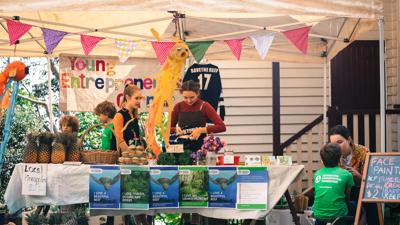 People at market stall, fundraising for ACF, banner visible.