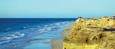 Kimberley landscape, red rock cliffs, green vegetation, blue sky, sunny day.