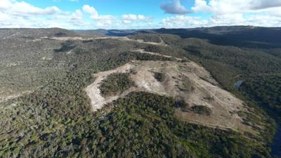 Deforestation scene, red-hued, trees felled, barren landscape, Red Range, Australia.
