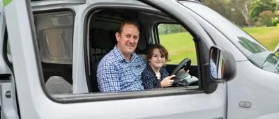 Dad and daughter smiling in an electric vehicle.