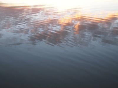 Reflection of a mountain range in calm water, blue sky above.