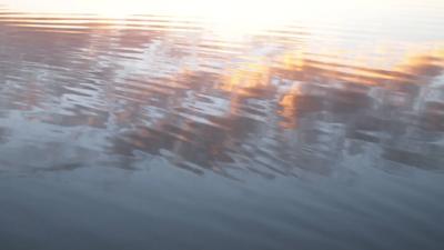Reflection of a mountain range in calm water, blue sky above.