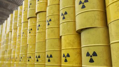 Nuclear waste drums stacked, metal containers, radioactive hazard symbol.