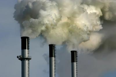 Smoke stacks billowing from a coal power plant tower.