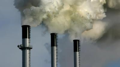 Smoke stacks billowing from a coal power plant tower.