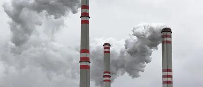 A polluted landscape with smoke, factories, and a dark sky.