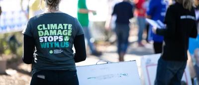 A polling booth scene with people, ballot boxes, and signage.