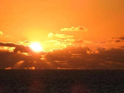 Pacific Ocean sunset over Australia, with sun and clouds.