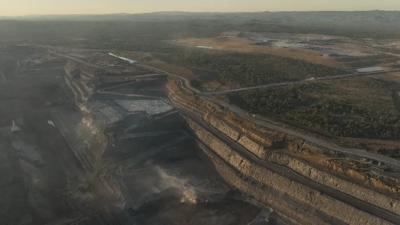 Open-cut coal mine, Hail Creek. Large machinery, vast landscape, brown earth, blue sky.