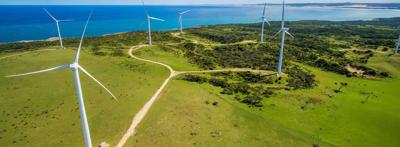 Coastal wind farm turbines against a blue sky.
