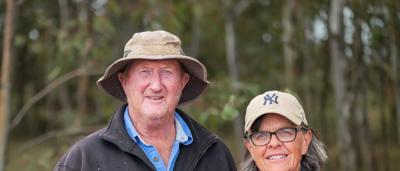 Two people, Jo and Greg, with a dog, in a field. Canary Island VIC farmers.