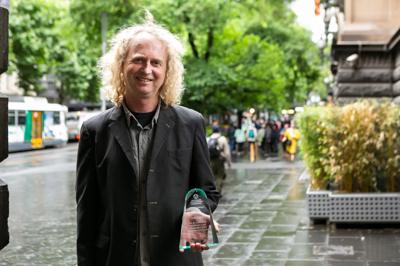 Man, Todd Dudley, holding award, smiling.