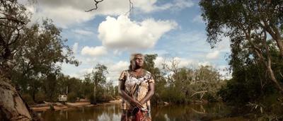 Woman, Yvonne Mirarr, smiling, holding a plant, outdoors, Jabiluka, post-win.