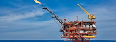 Offshore gas platform silhouette against a sunset sky.