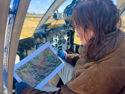 Close-up: Investigator in helicopter, reading map. Nandewar Range land clearing site.