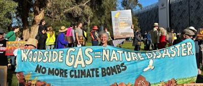 Woodside AGM: Crowd of people, stage with logo, presentation in progress.