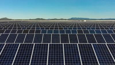 Solar farm landscape, rows of photovoltaic panels under a blue sky.