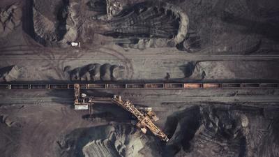 Coal pit, industrial landscape, smoke plumes, overcast sky.