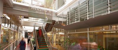 Green building with solar panels and trees.