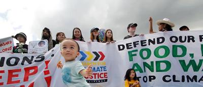 Woman in a white coat, holding a clipboard, smiling, standing in a lab setting.