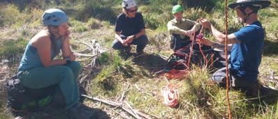 Woman smiling, camping near a canopy, trees in background.