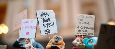 Woman in white coat, holding a plant, smiling.