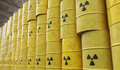 Nuclear waste drums stacked, metal containers, warning labels visible.