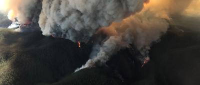 Fire engulfs buildings in Walhalla, Victoria, Australia. Smoke billows, flames visible.