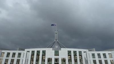Parliament House, Canberra. Australian flag flying, blue sky.