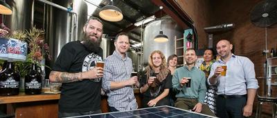 Wind turbine blades rotating against a blue sky, with a grassy field in the foreground.